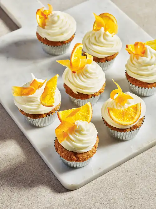 Iced cupcakes topped with orange slices and zest